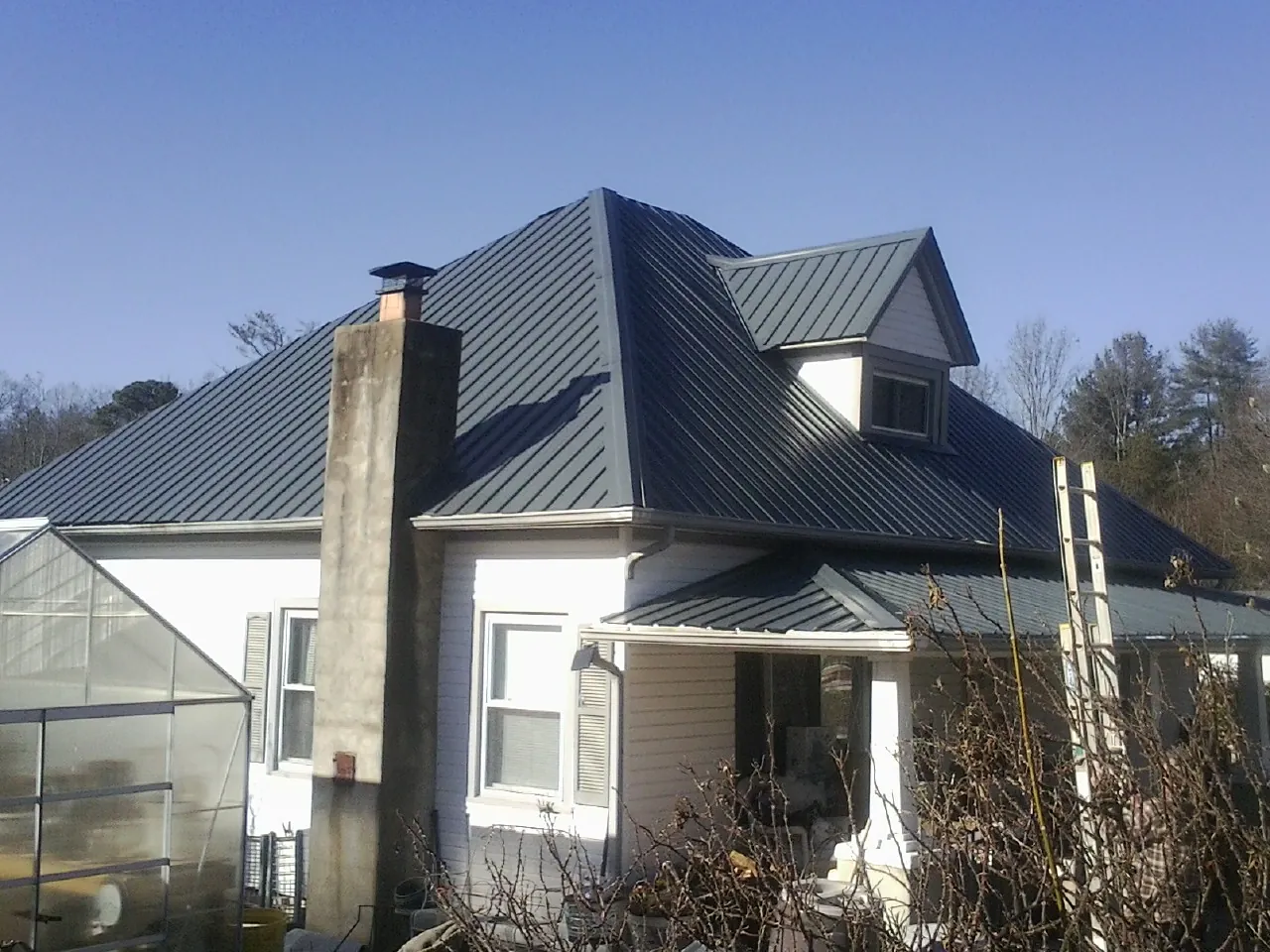 Dark blue standing seam metal roof on a white farmhouse with dormer — Slate & Tile Roof Repair by Roofing Brothers in Changewater