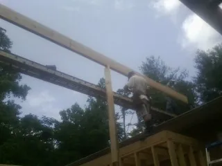 Carpenter setting a ridge beam over a new addition frame — Ice Dam Removal by Roofing Brothers in Changewater