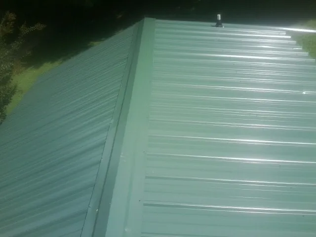 New green metal panels meeting at the ridge of a roof — Flat Roof Repair work by our crew in Changewater