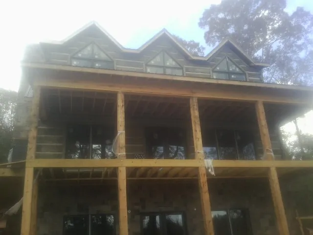 Dormers and porch framing on a large log home under construction — Roof Coating work by our crew in Changewater