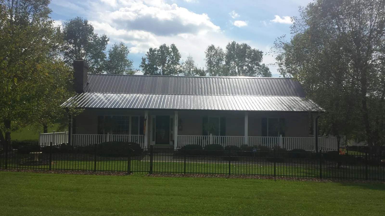 Gray metal roof on a brick ranch with a full width front porch — Gutter Guard Installation work by our crew in Changewater