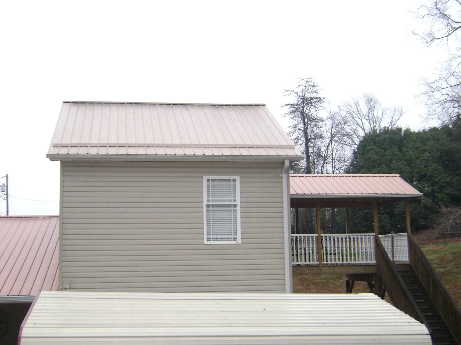 Tan metal roofs on a two story addition and attached porch, from a Roof Replacement job in Changewater