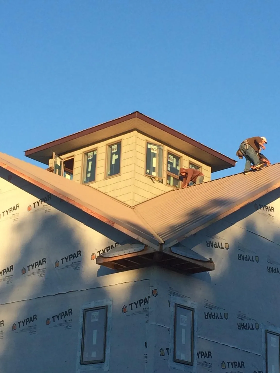 Roofers working around a rooftop cupola on a new metal roof at sunset — Roof Waterproofing in Changewater by Roofing Brothers